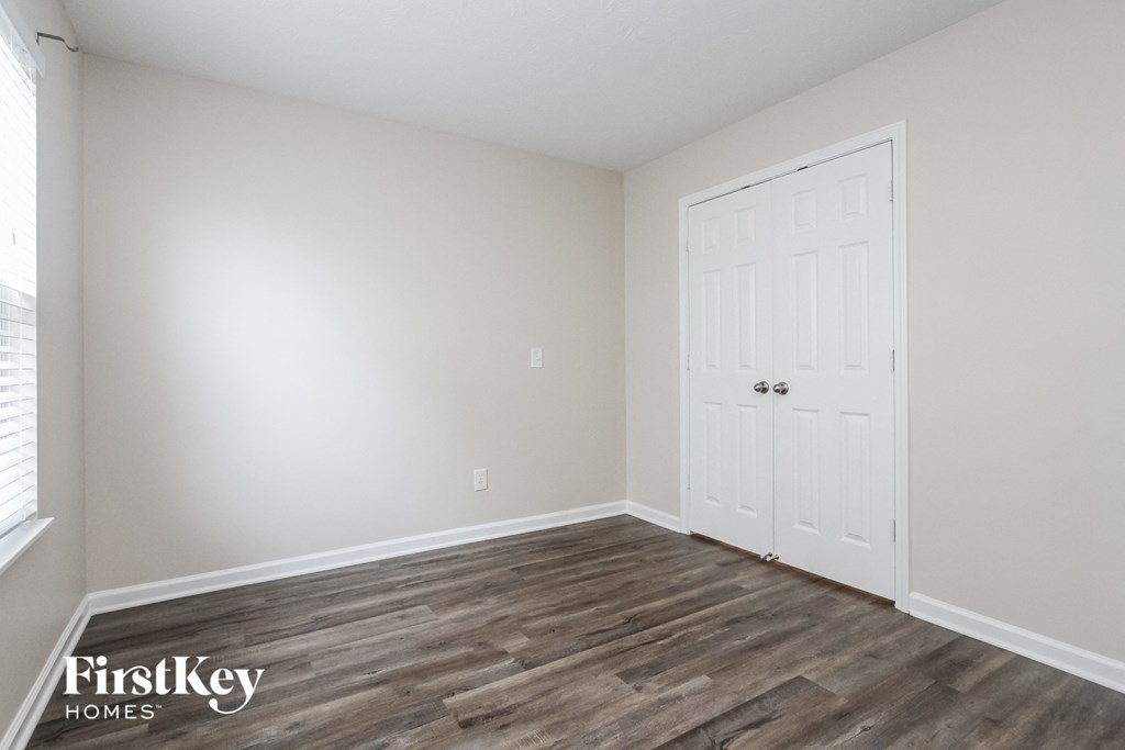 a bedroom with a white door and wood flooring
