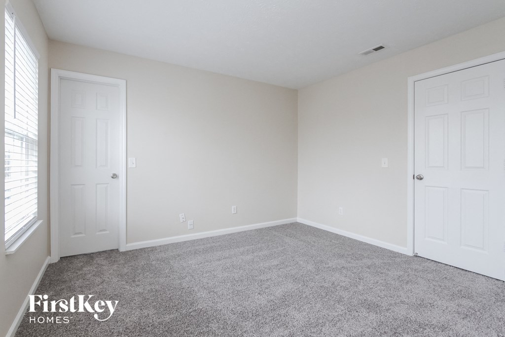 a bedroom with two doors and a carpeted floor