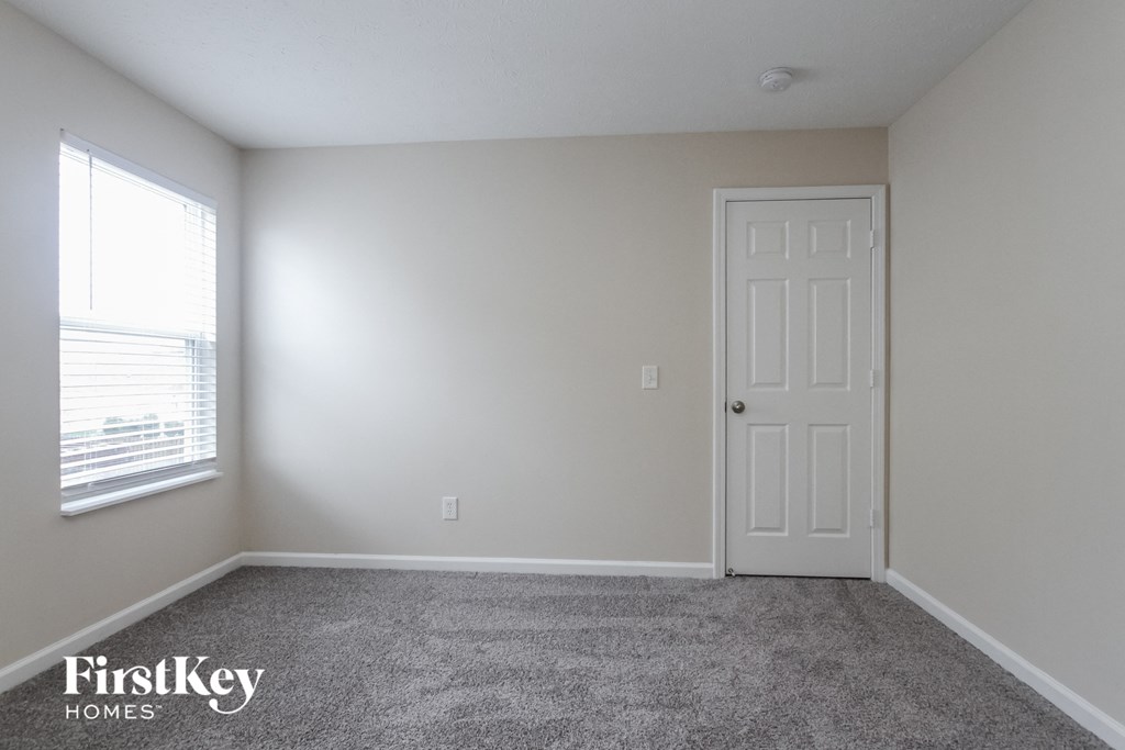 a room with carpet and a white door and a window