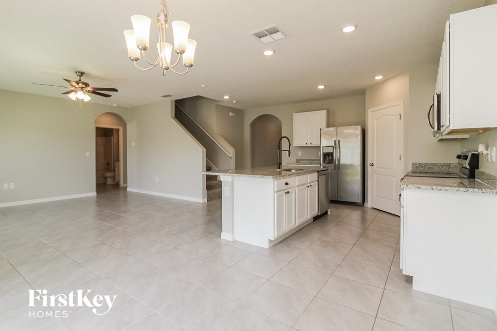 A spacious kitchen with a staircase leading to the upper floor.