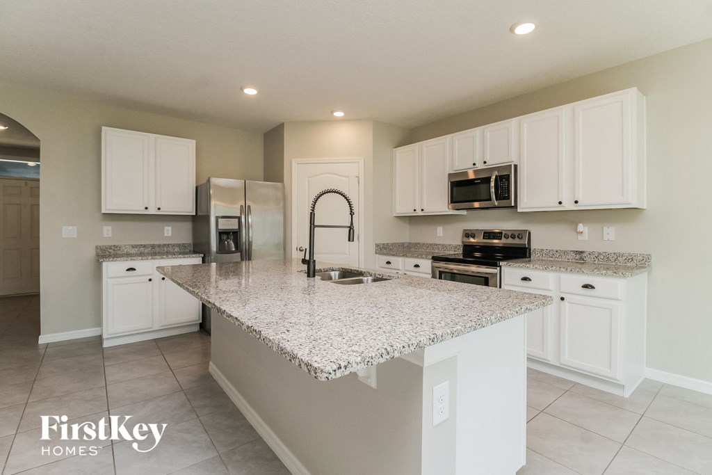 A kitchen with granite countertops and white cabinets.