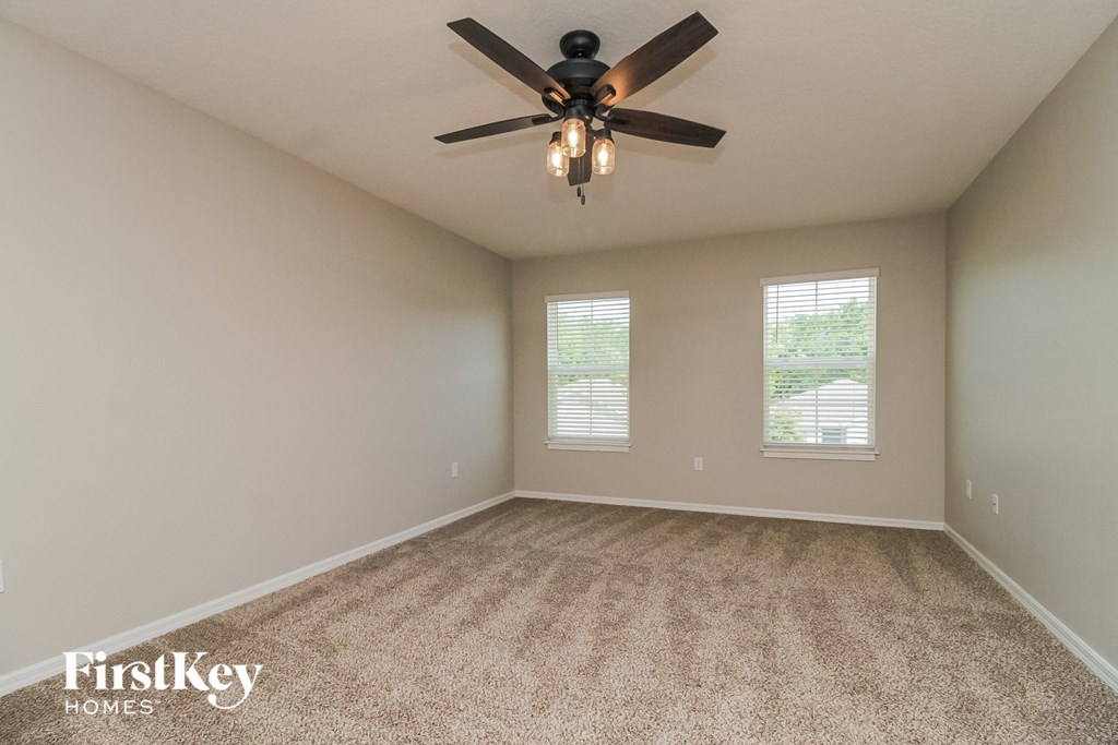 A room with a carpeted floor and a ceiling fan.