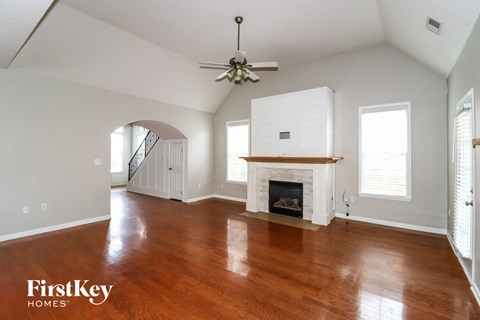 A spacious living room with a fireplace and a fan.