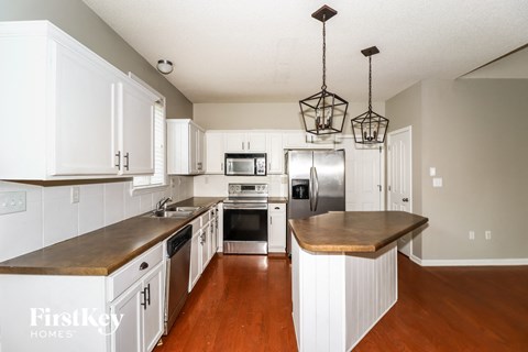 A kitchen with white cabinets and a wooden island.