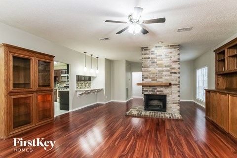 A spacious living room with wood floors and a stone fireplace.