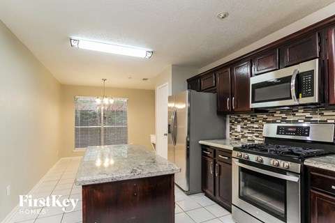 A kitchen with a granite countertop and stainless steel appliances.