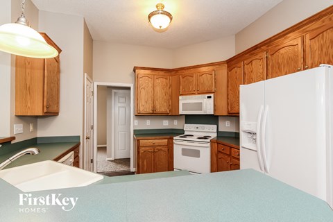 a kitchen with white appliances and wooden cabinets and green counter tops