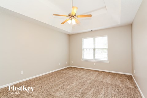 the spacious living room with ceiling fan and carpet
