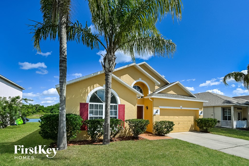 A yellow house with a palm tree in front.