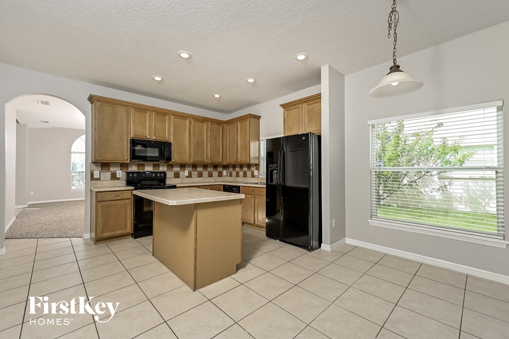 A kitchen with a refrigerator, microwave, and oven.