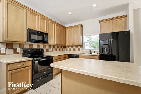 A kitchen with wooden cabinets and black appliances.