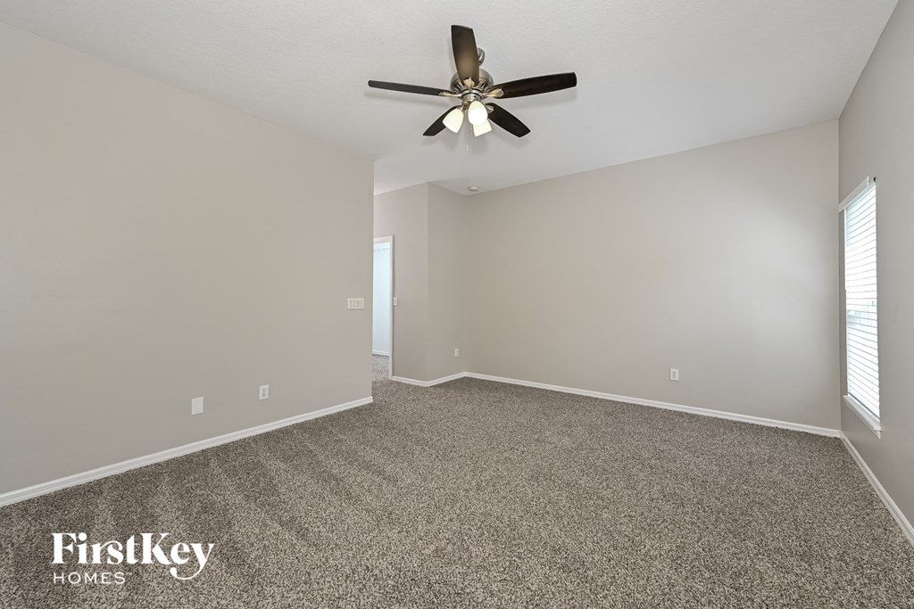 A room with a ceiling fan and carpeted floor.