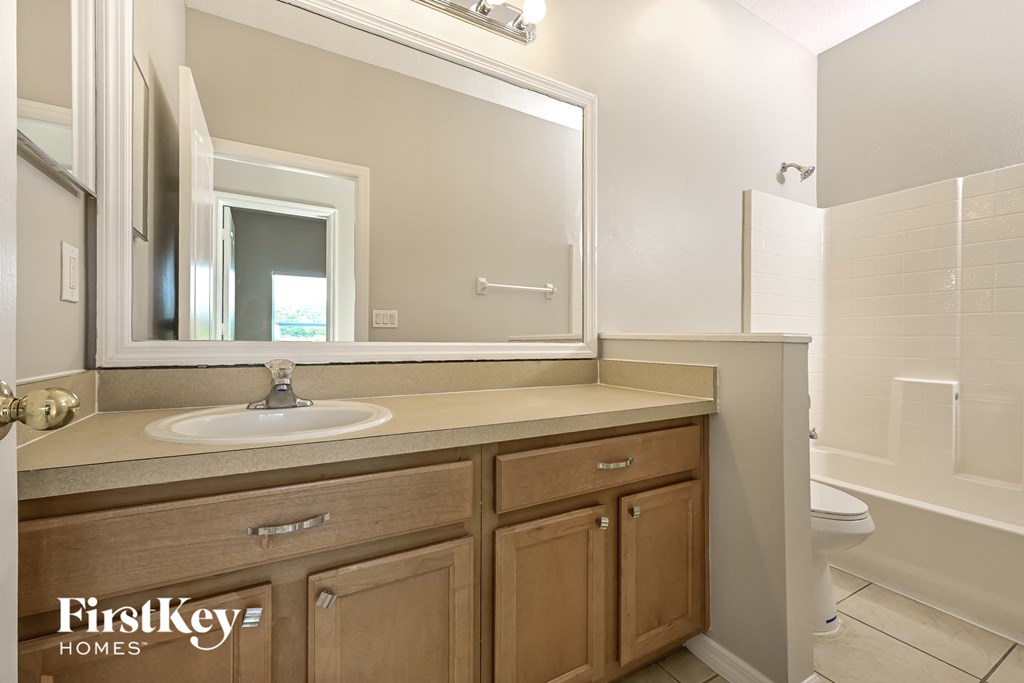 A bathroom with a sink, mirror, and wooden cabinets.