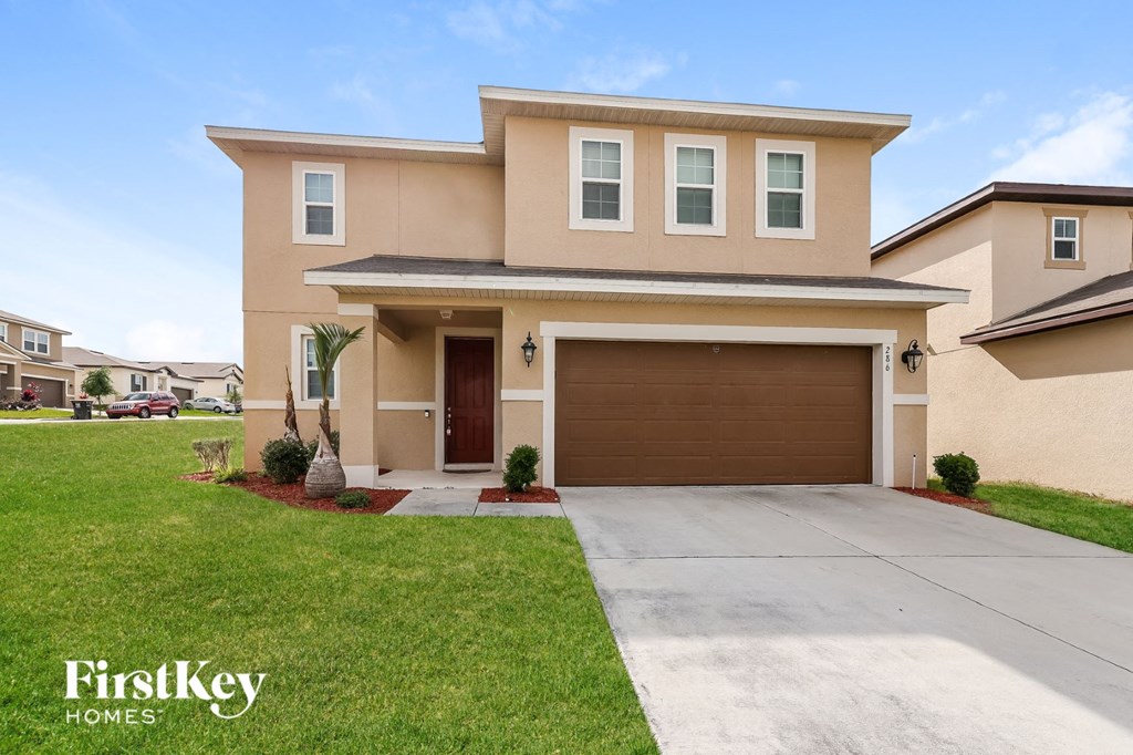 a beige house with a driveway and a garage door
