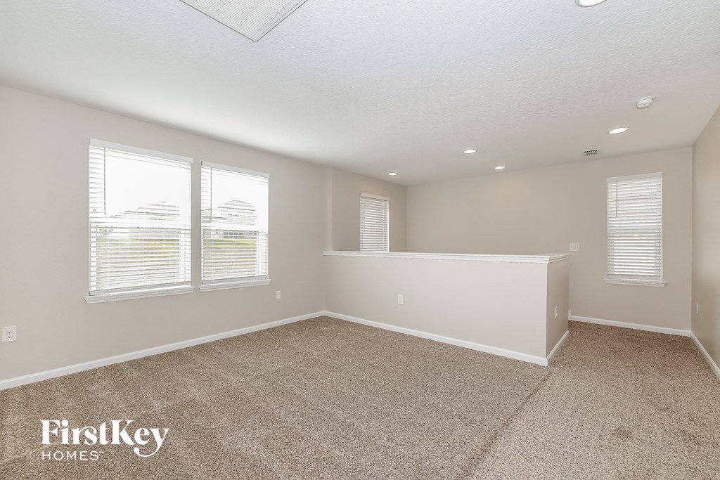 the living room of an empty home with carpet and windows
