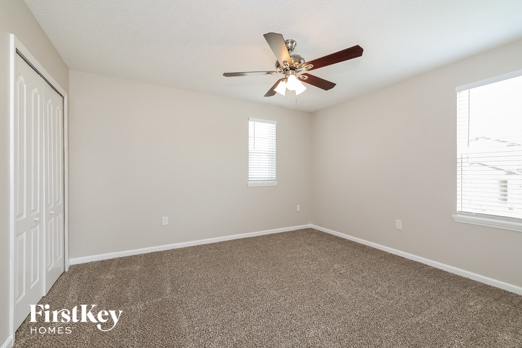 the spacious living room with ceiling fan and carpeting