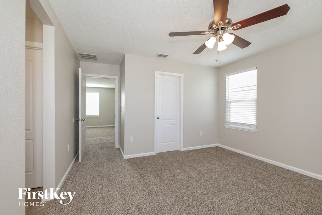 an empty living room with a ceiling fan and a closet