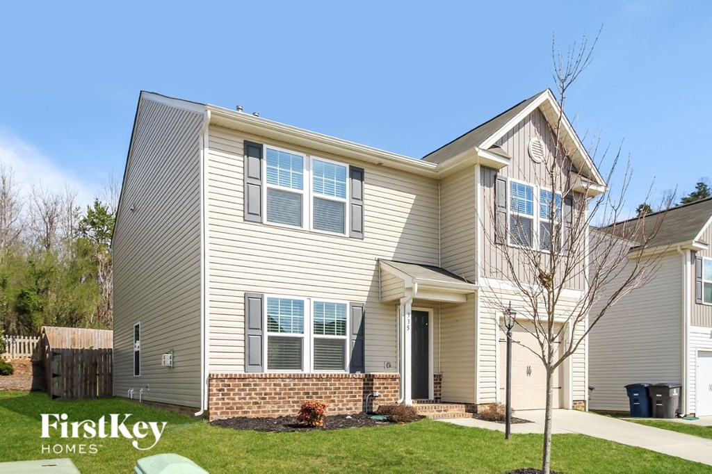 a beige house with white siding and a lawn