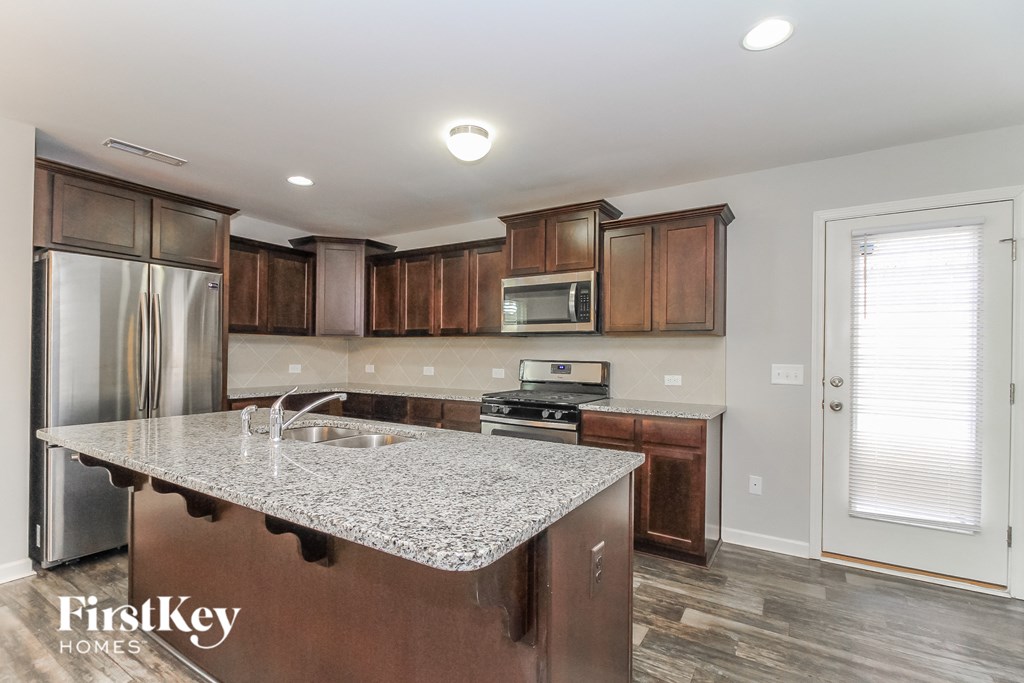 a kitchen with wooden cabinets and a granite counter top and a stainless steel refrigerator