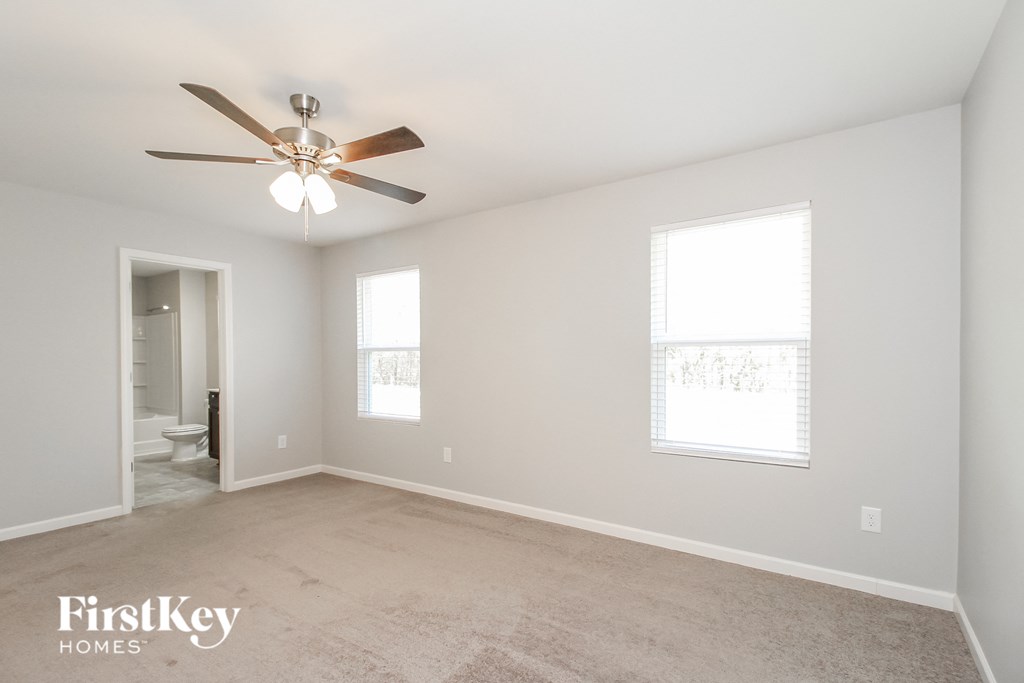 an empty living room with a ceiling fan and a bathroom