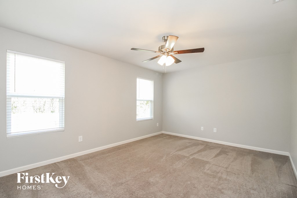 an empty room with a ceiling fan and two windows