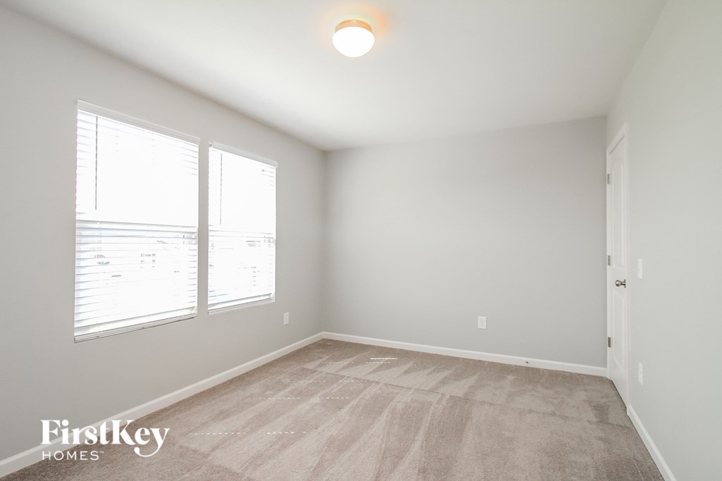 the living room of an apartment with a carpeted floor and two windows