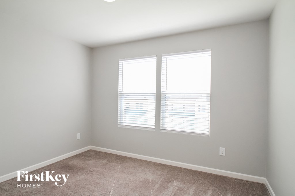 a bedroom with two windows and a carpeted floor