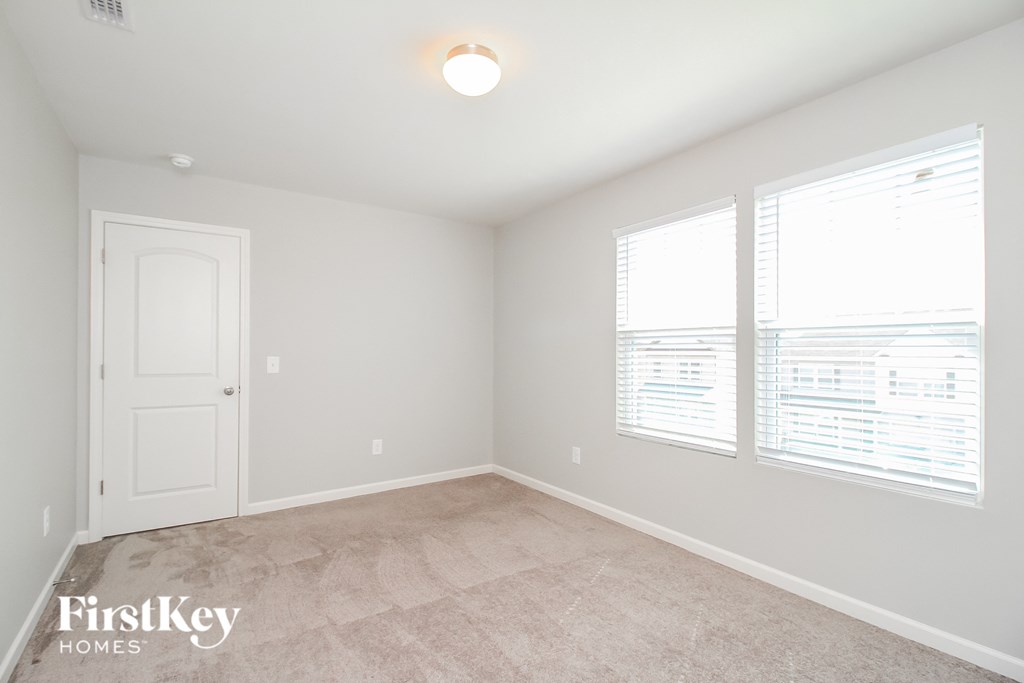 a bedroom with a carpeted floor and three windows
