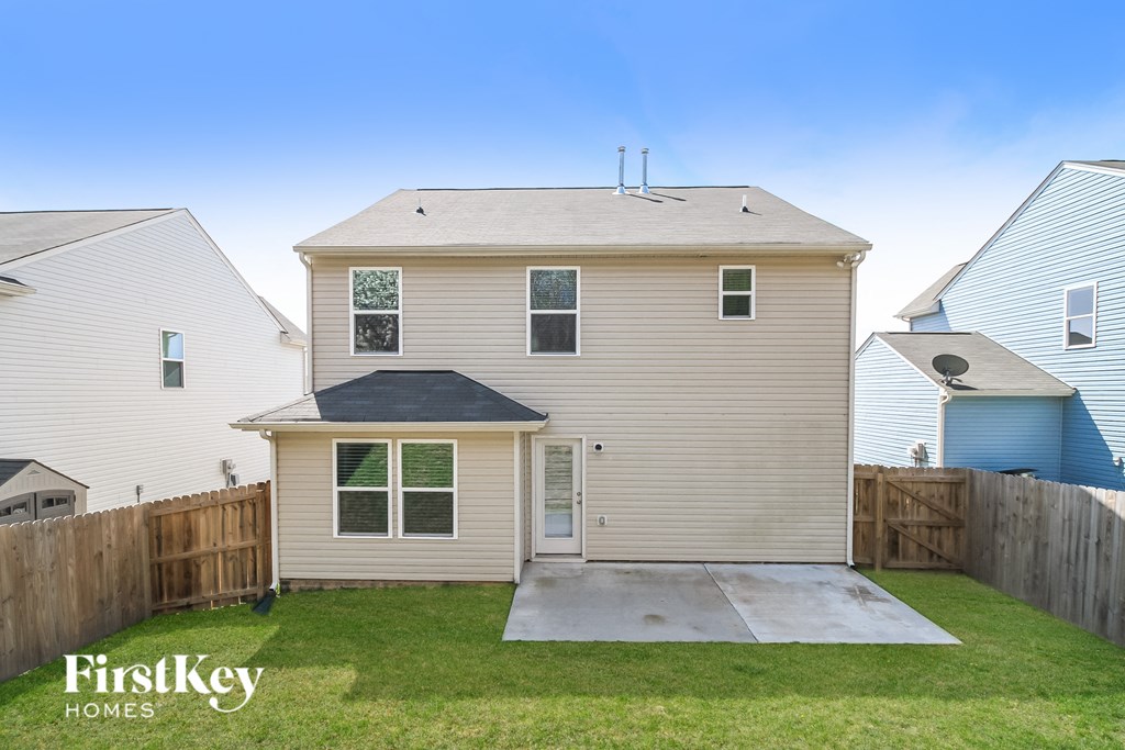 the back of a house with a yard and a sidewalk