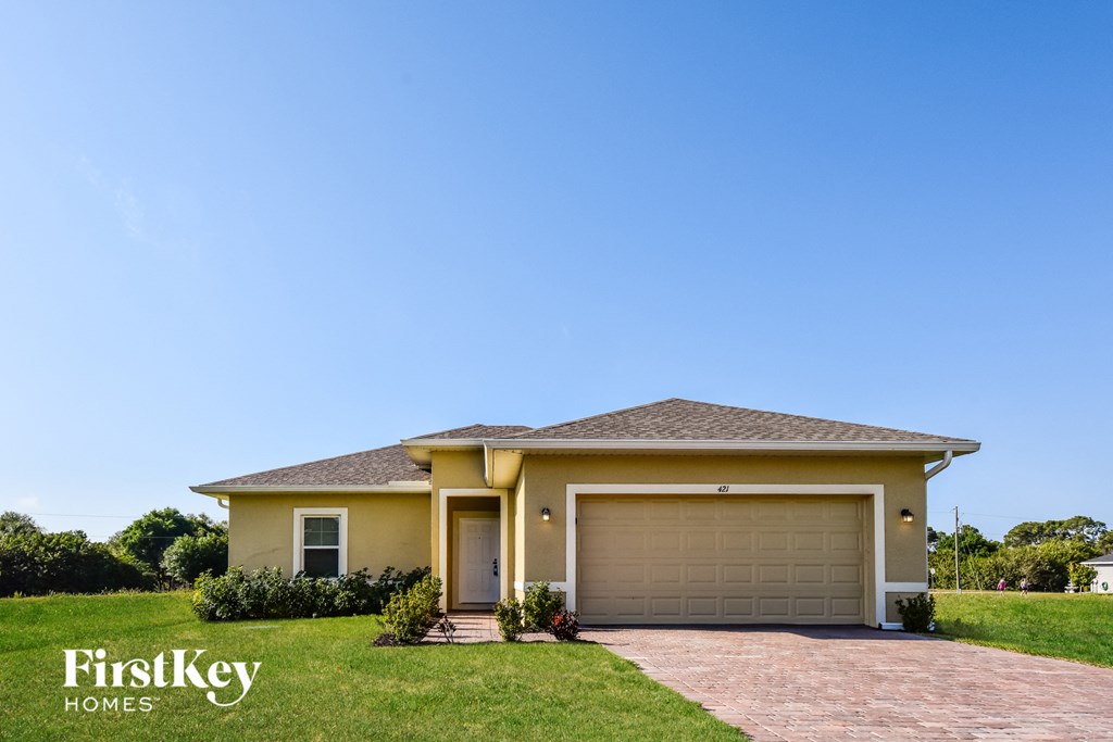 A house with a garage door and a brick pathway leading to it.