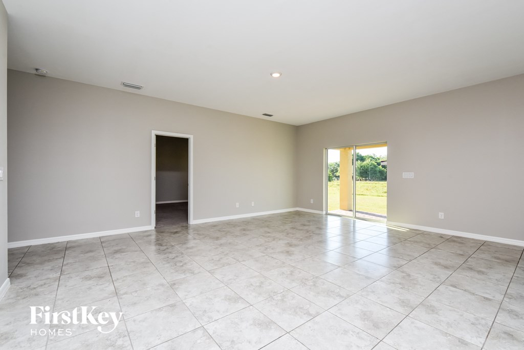 A spacious room with a tile floor and a sliding glass door leading to a balcony.