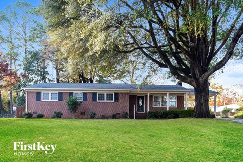 a red brick house with a large tree in the yard