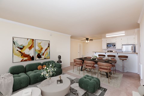 A living room with a green couch and a dining table with chairs.