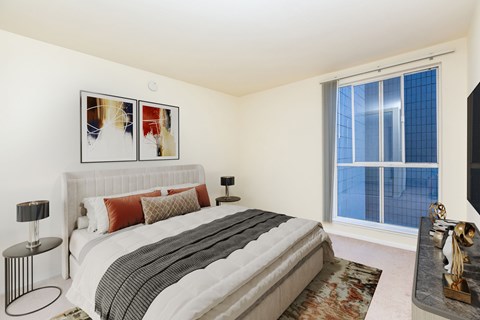 A bedroom with a large bed, a nightstand with a lamp, and a painting on the wall.