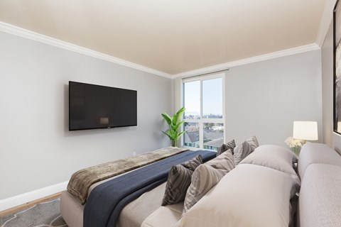 A living room with a couch and a flat screen TV mounted on the wall.
