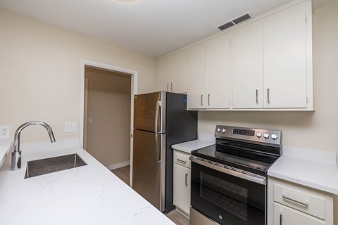A kitchen with white cabinets and a black fridge.