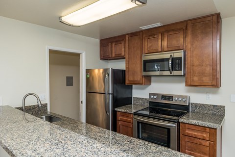 A kitchen with a granite countertop and stainless steel appliances.