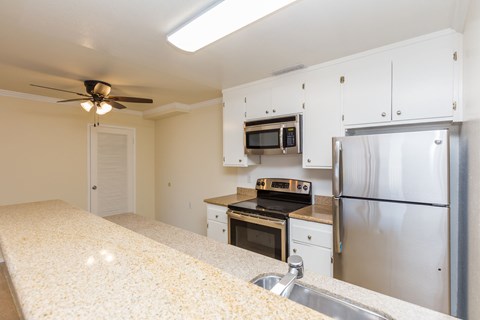 A kitchen with a stove, refrigerator, and microwave.