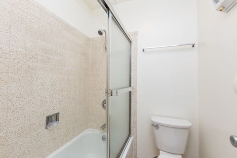 A white toilet sits next to a glass shower door.