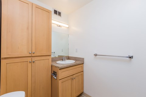 A bathroom with a sink, toilet, and cabinets.