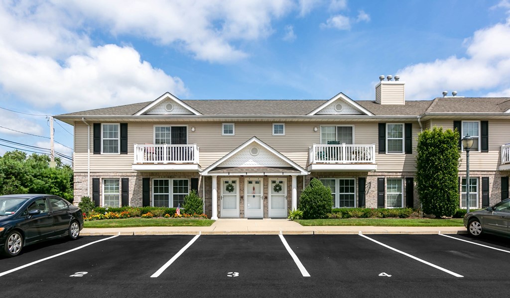 the front of an apartment building with a parking lot