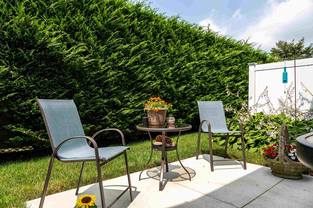 a patio with three chairs and a table on a patio