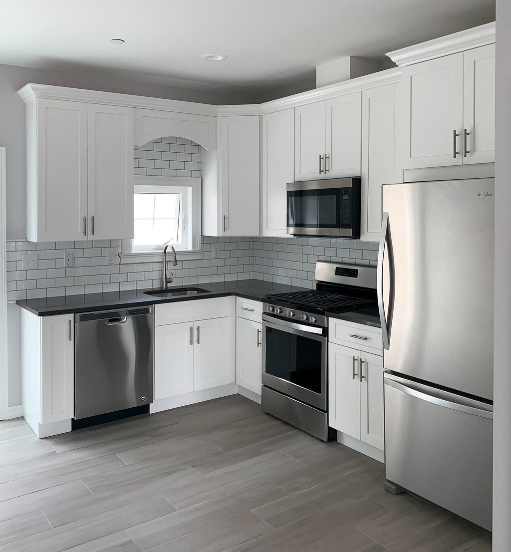 a white kitchen with stainless steel appliances and white cabinets