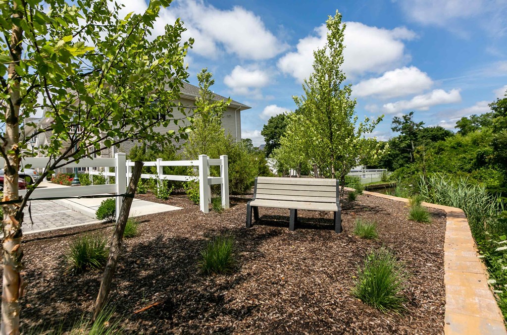 a bench sitting in a garden next to a fence