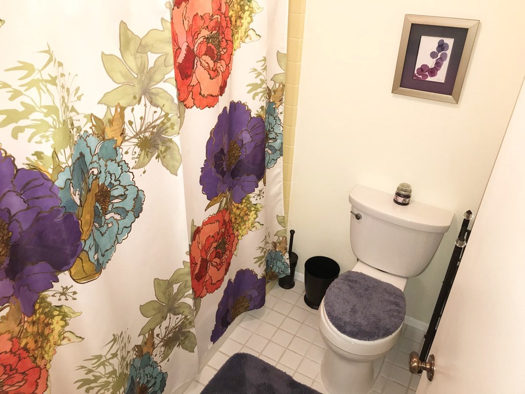 a bathroom with a toilet and a shower curtain with flowers