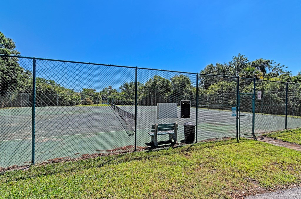a tennis court with a bench in front of a fence