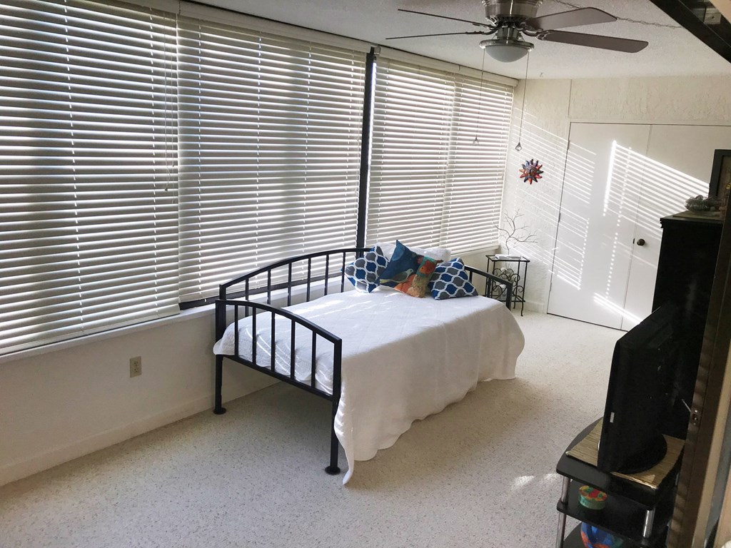 a bedroom with a bed and windows with blinds and a ceiling fan