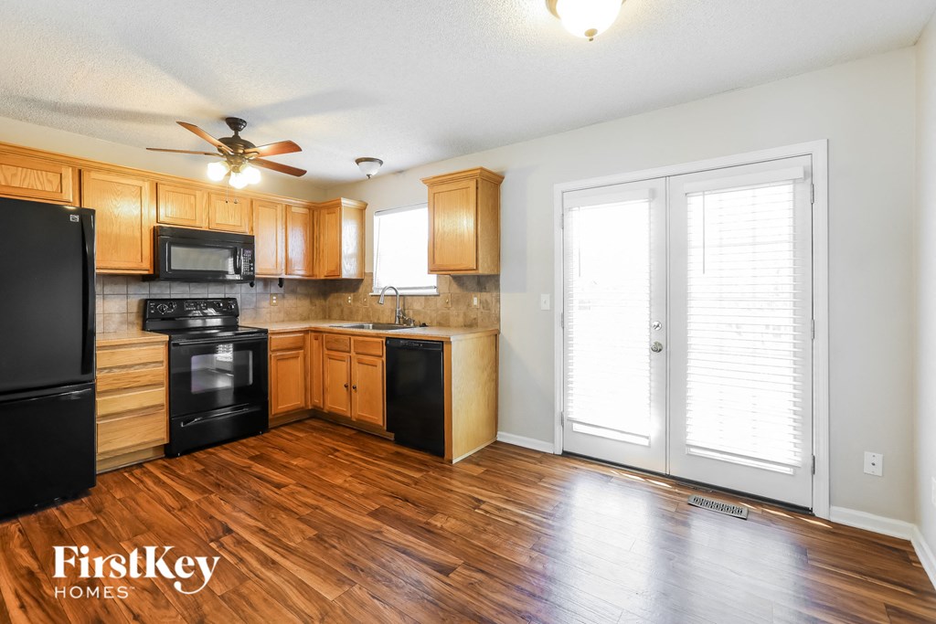 a kitchen with wood flooring and wooden cabinets and a window