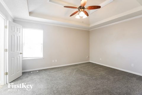 the living room of a home with carpet and a ceiling fan