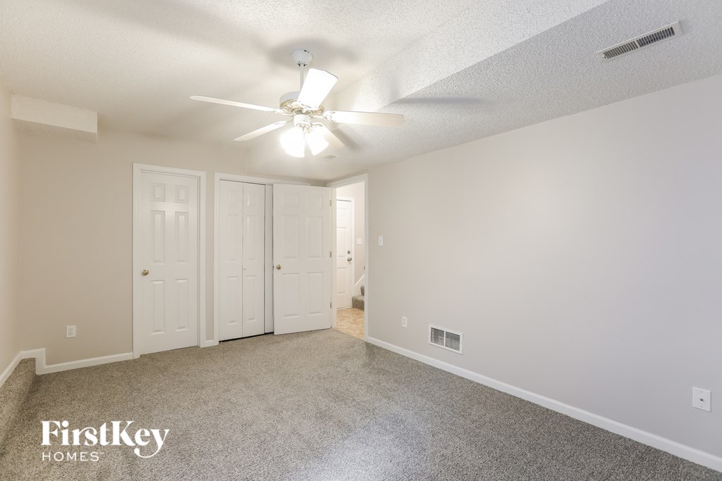 a spacious living room with carpet and a ceiling fan